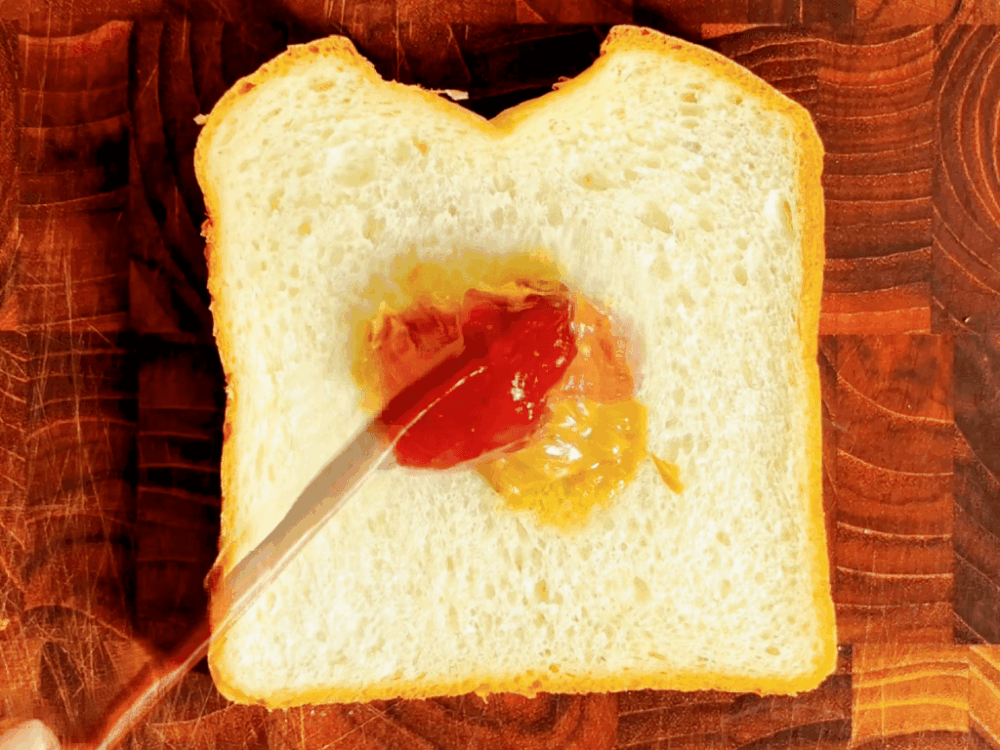 Spreading strawberry jam on bread