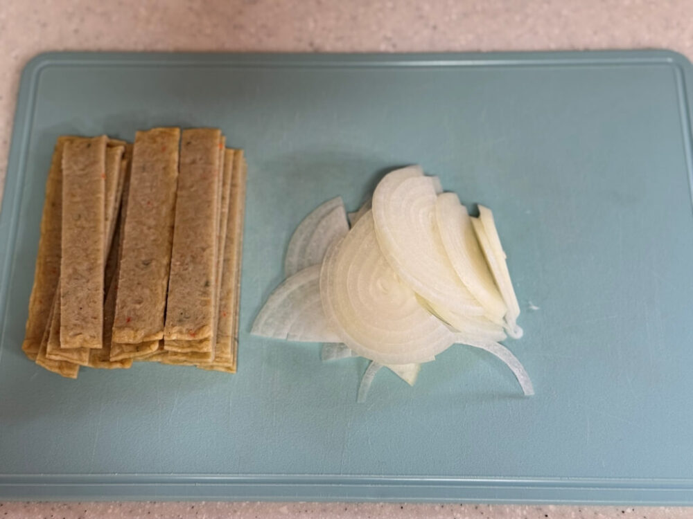 Pasteles de pescado y cebollas en la tabla de cortar.