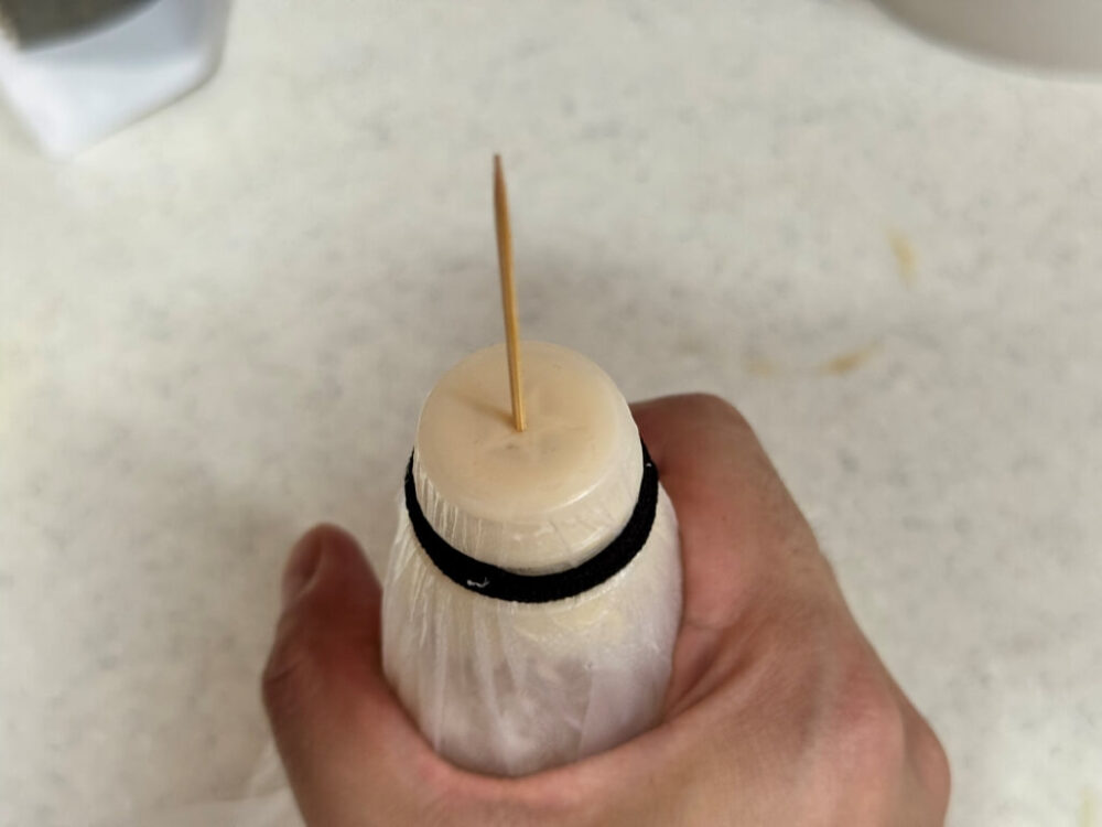 The opening of the mayonnaise is wrapped in plastic wrap, secured with a rubber band, and pierced with a toothpick.