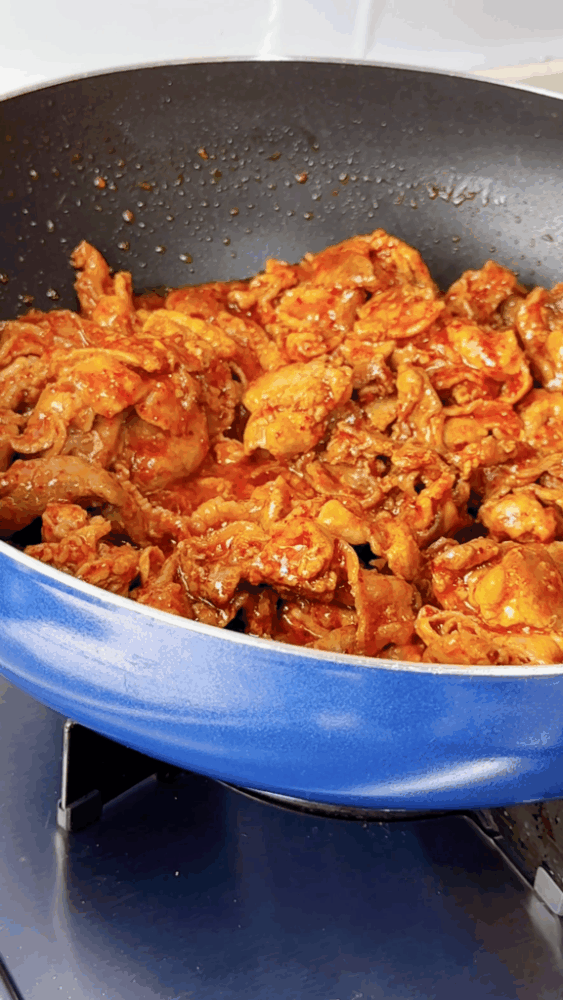 The pork is stained red as it simmers in the marinade.